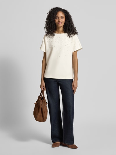 Vrouwenmodel draagt T-shirt met ronde hals en parels van Christian Berg Woman, materiaalmix met modal, relaxed fit, wit. Volledige lichaamsvooraanzicht.