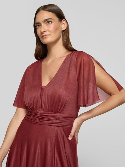 Modelka prezentuje 'Schimmerndes Maxikleid mit V-Ausschnitt und Taillenband' od Christian Berg Cocktail, siateczka, linia a, efekt błyszczący, dekolt w serek, tasiemka w talii, długość tyłu w rozmiarze 36: 149 cm, szerokość klatki piersiowej w rozmiarze 36: 35 cm, długość rękawów w rozmiarze 36: 29 cm, połyskliwe odcienie bordo, proste linie, lekka struktura, zbliżenie na górną część ciała
