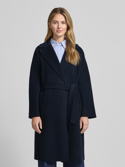 Frauenmodel trägt Regular Fit Wollmantel aus Schurwoll-Mix Modell 'CIVADA' von Weekend Max Mara in Dunkelblau mit Bindegürtel und seitlichen Taschen, unifarbene Optik, Nahaufnahme Oberkörper.