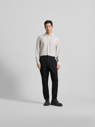Männermodel trägt Straight Fit Stoffhose aus reiner Wolle von Officine Générale, schwarz, vorne Bundfalten, Ganzkörperansicht von vorne.