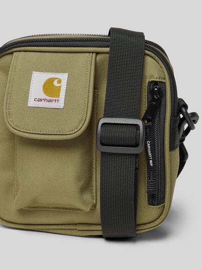 Produktfoto, Umhängetasche mit Label-Patch von Carhartt Work In Progress in Olivgrün mit Reißverschluss, Reißverschlusstasche und verstellbarem Schulterriemen, Maße: Breite 16 cm, Länge 17 cm, Tiefe 6 cm, Schulterriemen 71 cm, robuste Stofftextur