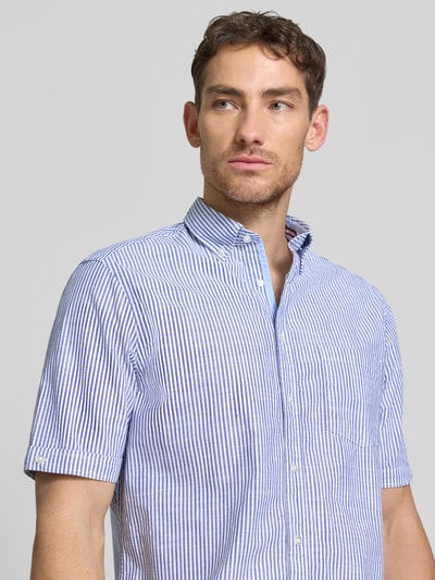 Męski model nosi Regular Fit Freizeithemd mit Brusttasche von Christian Berg Men, bawełna, kołnierzyk typu button down, niebieskie paski, z krótkim rękawem i listwą guzikową, brustasza, Szerokość w rozmiarze M: 47 cm, długość tyłu: 79 cm, długość rękawów: 26 cm, koszula casualowa, całkowity widok górnej części ciała z przodu