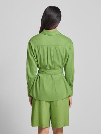 Frauenmodel trägt Bluse aus Leinen-Mix mit Brusttaschen von Marc Cain in leuchtendem Grün, taillierte Passform, Stoffband, Umlegekragen, Ganzkörperansicht Rückansicht. Rückenlänge bei Größe 36: 69 cm, Ärmellänge bei Größe 36: 55 cm, elastischer Leinen-Mix mit Viskose-Anteil.