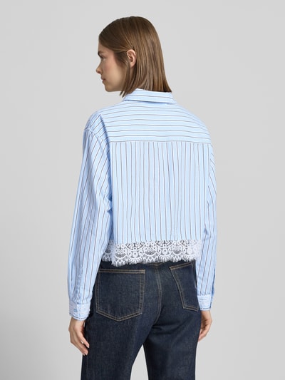 Vrouwenmodel draagt Boxy Fit langarmblouse van pure katoen Modell 'KHALIDA' van Only met allover gestreept patroon en kanten details, fijne geweven textuur, eenrijige knoopsluiting, borstzak; lichte en donkere blauwtinten, achteraanzicht volledige lichaamsopname.