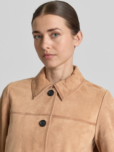Frauenmodel trägt Lederjacke aus Ziegenvelours mit Pattentaschen von More & More, sandfarben, Knopfleiste, Nahaufnahme Oberkörper. Rückenlänge bei Größe 36: 54 cm, Schulterbreite: 37 cm, Brustweite: 51 cm, Ärmellänge: 60 cm, Regular-Fit, Umlegekragen.