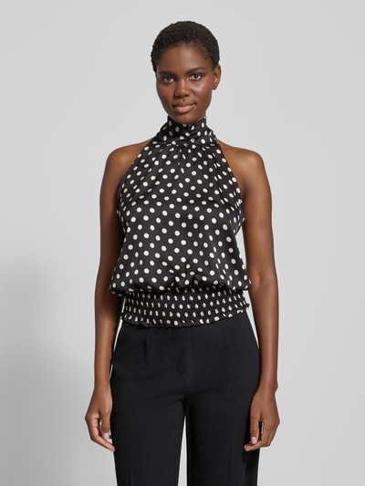 Frauenmodel trägt Blusentop im Allover-Look von Neo Noir in Schwarz mit weißen Punkten, Stehkragen, rückseitige Schnürung, Regular Fit, Rückenlänge 50 cm bei Größe 36, Ganzkörperansicht von vorne.