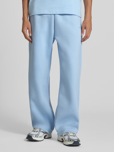 Männermodel trägt Straight Fit Sweatpants Baumwoll-Mix von REVIEW in Hellblau mit Elastikbund und Gesäßtasche, Nahaufnahme Unterkörper.