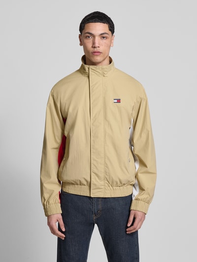 Männermodel trägt Regular Fit Blouson mit Logo-Stitching von Tommy Hilfiger in Beige, unifarben, Satin, Stehkragen, Ganzkörperansicht von vorne.