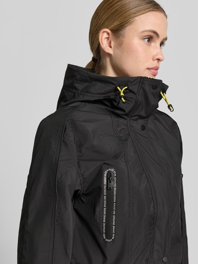Frauenmodel trägt schwarze Jacke mit Reißverschlusstaschen Modell 'AMELIA' von khujo, gelbe Details, Nahaufnahme Oberkörper.