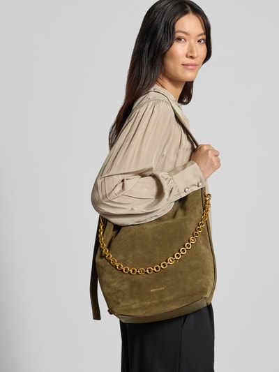 Frauenmodel trägt Handtasche aus Leder mit Label-Applikation Modell 'NOLITA' von MICHAEL Michael Kors in Olivgrün mit Goldkette, Hauptfach mit Magnetverschluss, Schulterriemen, Ganzkörperansicht von vorne.