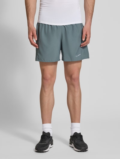Männermodel trägt Shorts mit seitlichen Eingrifftaschen und Logo-Print von NIKE TRAINING in Grau, Loose-Fit, elastischer Bund, Ganzkörperansicht von vorne.