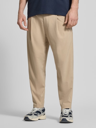 Männermodel trägt Spodnie z zakładkami w pasie Relaxed Fit Bundfaltenhose mit Viskose-Anteil Modell 'VIGGO CROPPED' von Marc O'Polo Denim, efekt: jednolity kolor, krój relaxed fit, średni stan, długość krótka, tunel, wyhaftowane logo, zakładka w pasie, elastyczny pas, wpuszczane kieszenie boczne, kieszenie z tyłu, mieszanka materiałów z dodatkiem wiskozy, całość w jasnobeżowym kolorze, materiał gładki, Ganzkörperansicht von vorne