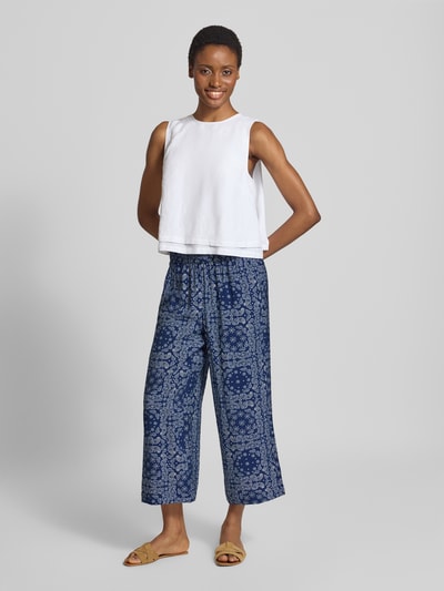 Frauenmodel trägt Relaxed Fit Culotte aus Viskose-Mix von s.Oliver RED LABEL in Blau mit weißem Muster und weißem Top, Ganzkörperansicht von vorne.