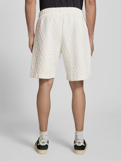 Mężczyzna nosi Shorts mit Logo-Stitching Modell 'Jovren' od Pegador, mix materiałów z bawełną, krój loose fit, elastyczny pas, boczne kieszenie, kolor kremowy, tekstura pikowana, szerokość w rozmiarze M: 38 cm, długość nogawki wewnętrznej: 24 cm, widok całej sylwetki z tyłu.
