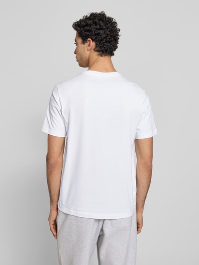 Männermodel trägt T-Shirt mit Label-Stitchings und Rundhalsausschnitt von CHAMPION in Weiß, Reine Baumwolle, Regular-Fit, Rückenlänge 69 cm, Ganzkörperansicht Rückansicht.