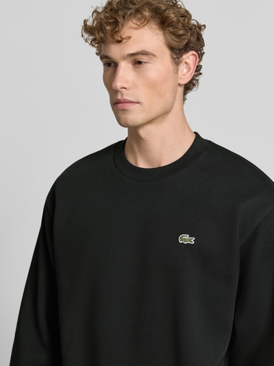 Männermodel trägt Regular Fit Sweatshirt aus Baumwoll-Mix von Lacoste in Schwarz mit gesticktem Logo, Nahaufnahme Oberkörper, Herren Sweatshirt von Lacoste.