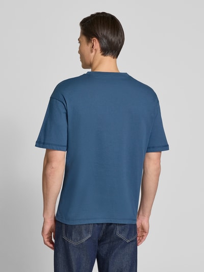 Männermodel trägt Regular Fit T-Shirt mit Label-Schriftzug aus reiner Baumwolle von Tommy Hilfiger in Blau, Ganzkörperansicht Rückansicht.