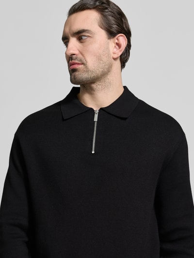 Männermodel trägt Relaxed Fit Pullover aus Viskose-Mix Modell 'TELLER' von SELECTED HOMME in Schwarz, Feinstrick, Nahaufnahme Oberkörper.