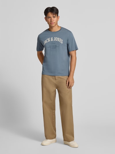 Männermodel trägt Regular Fit T-Shirt aus reiner Baumwolle Modell 'Denver' von JACK & JONES in Blau mit Logo-Print, Ganzkörperansicht von vorne. Rückenlänge bei Größe M: 69 cm.