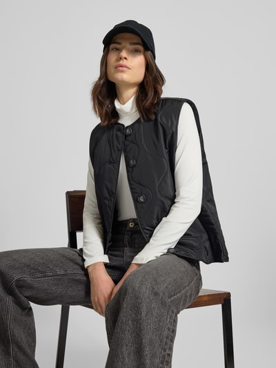 Vrouwenmodel draagt Regular fit bodywarmer met eenrijige knoopsluiting model 'MILLIE' van Vero Moda, look: effen, steekzakken, materiaalverwerking: doorgestikt. Nahaufnahme Oberkörper.