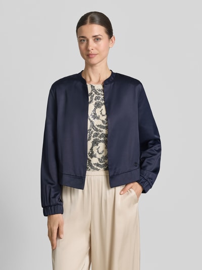 Frauenmodel trägt Slim Fit Blazer aus Viskose-Mix von s.Oliver BLACK LABEL in Optik: Unifarben, College-Kragen, Langarm, Label-Detail, ganzkörperansicht von vorne.