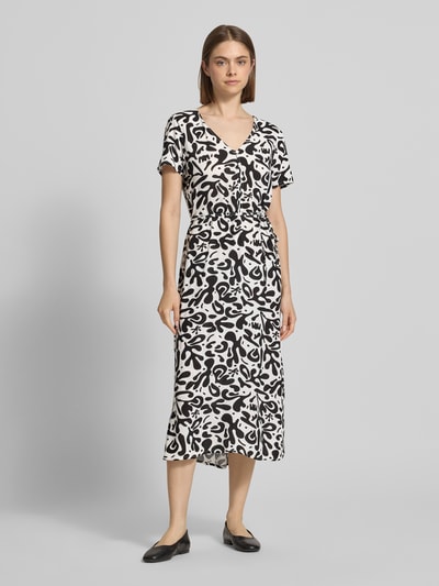 Frauenmodel trägt A-Linien Midikleid aus reiner Viskose Modell 'BARRI' von Pieces mit Allover-Muster in Schwarz-Weiß, Ganzkörperansicht von vorne.