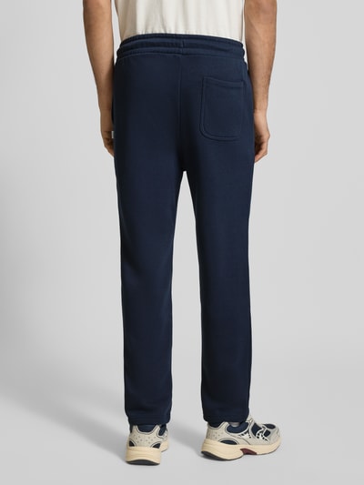 Männermodel trägt dunkelblaue Sweatpants mit Baumwoll-Anteil Modell 'KANE BRADLEY' von JACK & JONES, Gerade Passform, Ganzkörperansicht Rückansicht.