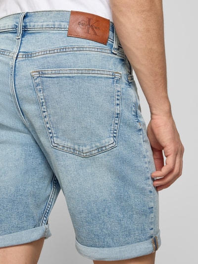 Männermodel trägt Slim Fit Jeansshorts aus Baumwoll-Mix Modell 'ABNER' von Calvin Klein Jeans in Denim-Optik mit Label-Patch, Detailaufnahme Rückansicht.
