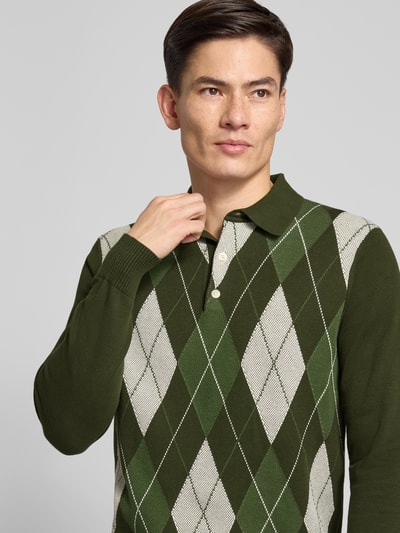 Männermodel trägt Regular Fit Strickpullover aus reiner Baumwolle von Tommy Hilfiger mit Optik: Unifarben, Muster: Gitterkaro, Nahaufnahme Oberkörper.