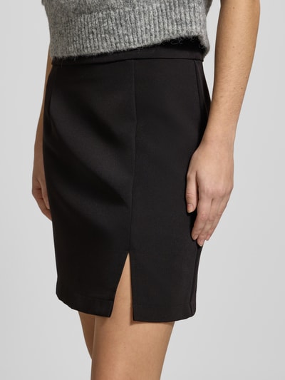 Frauenmodel trägt ausgestellten, schwarzen Mini-Rock mit Saumschlitz, elastischem Bund und Reißverschluss, Modell 'BOZZY' von Pieces, Nahaufnahme Oberkörper.