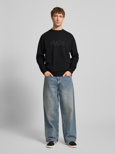 Męski model nosi Regular Fit bluzę z czystej bawełny Model 'NIEROFIX_CREW' od Hugo Blue, efekt: jednolity kolor, nadruk z logo, dzianina dresowa, okrągły dekolt, długi rękaw, prążkowane wykończenia. Ganzkörperansicht von vorne.