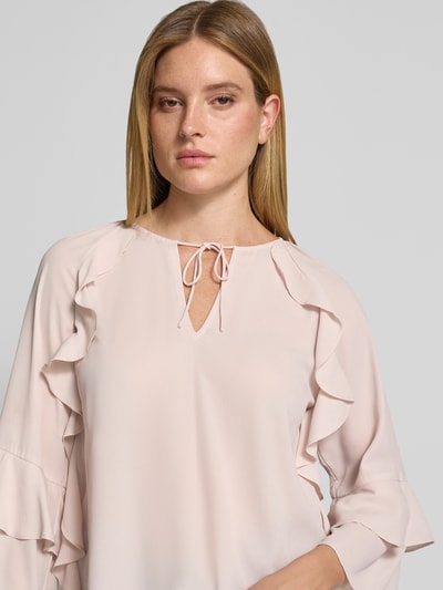 Frauenmodel trägt Regular Fit Bluse mit Schlüssellochausschnitt von monari in hellem Rosa mit Rüschenbesatz, Nahaufnahme Oberkörper.