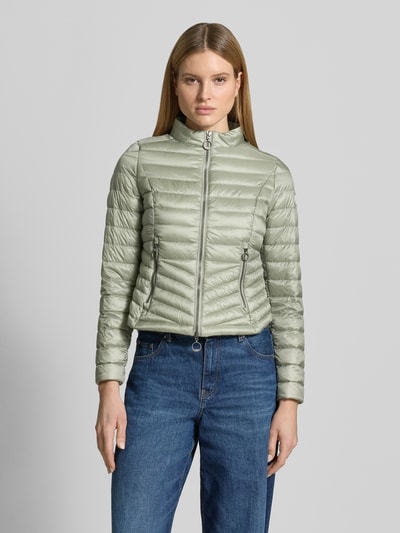 Frauenmodel trägt Steppjacke mit Stehkragen von Gil Bret in hellem Grün, Zweiwege-Reißverschluss, Reißverschlusstaschen, Körpernahe Passform, Rückenlänge 56 cm, Schulterbreite 39 cm, Brustweite 47 cm, Ärmellänge 66 cm, Ganzkörperansicht von vorne.