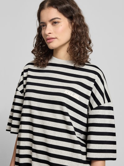 Frauenmodel trägt Oversized T-Shirt mit Label-Print von Karo Kauer aus reiner Baumwolle, schwarz-grau gestreift, Nahaufnahme Oberkörper.