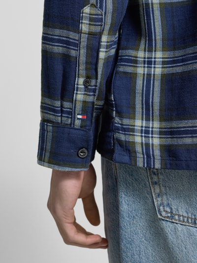 Männermodel trägt Relaxed Fit Freizeithemd aus reiner Baumwolle von Tommy Hilfiger in blau-grünem Gitterkaro-Twill, Nahaufnahme Unterarm.