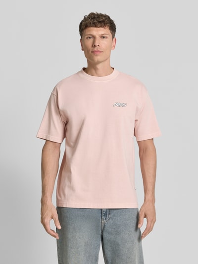 Männermodel trägt Regular Fit T-Shirt aus reiner Baumwolle Modell 'SURFWASH' von BOSS Orange, unifarben, Label Print, Rundhals, kurzarm, Jersey, Ganzkörperansicht von vorne.