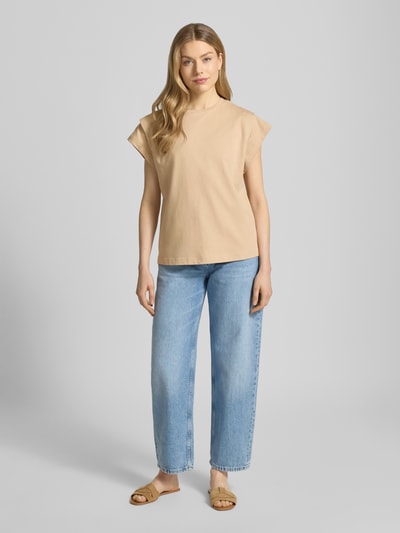 Kobiece model nosi damski t-shirt z krótkimi rękawami z bawełny, prosty krój, model 'PIO' od Bash, okrągły dekolt, długość tyłu w rozmiarze S: 58 cm, jasnobeżowy, gładka faktura, pełna sylwetka z przodu.