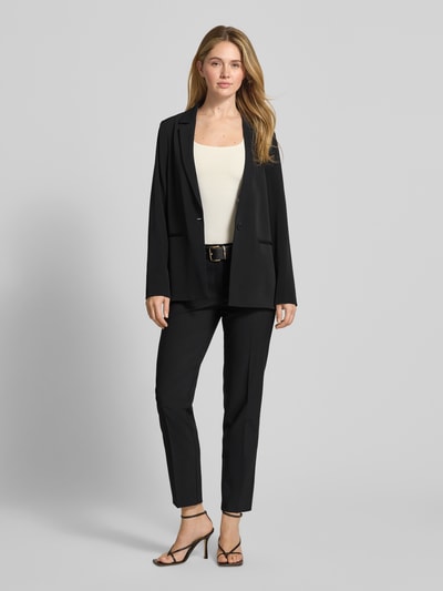 Kobiece modelka nosi Relaxed Fit Blazer mit Reverskragen od comma, elastyczna mieszanka materiałów, krój relaxed fit, kołnierz z połami, zapięcie na guzik, kieszenie z wypustkami, długość tyłu w rozmiarze 36: 70 cm, szerokość w rozmiarze 36: 49 cm, długość rękawów w rozmiarze 36: 63 cm, czarny kolor, jednolita tekstura, całkowity widok z przodu.