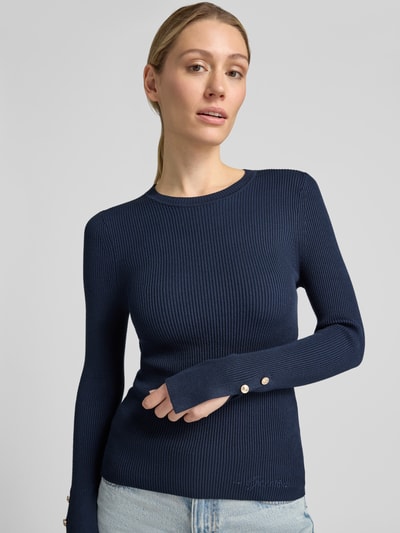 Vrouwenmodel draagt slim fit shirt met lange mouwen van viscosemix model 'Ellie' van GUESS, met strass-steentjes en logodetail, donkerblauw, ribstructuur, ruglengte maat S 58 cm, mouwlengte 63 cm, Nahaufnahme Oberkörper.