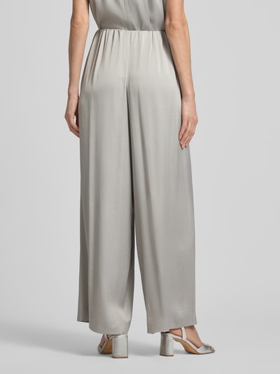 Modelka nosi Loose Fit Stoffhose mit Stretch-Anteil od Drykorn, mieszanka acetatu i elastanu, krój loose fit, elastyczny pas, szerokie nogawki, szerokość w rozmiarze 27/34: 35 cm, długość wewnętrzna nogawki: 76 cm, kolor jasnoszary, gładka tekstura, widok całej sylwetki z tyłu.