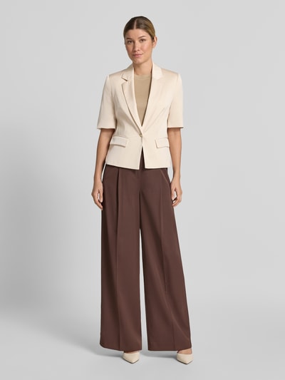 Frauenmodel trägt Slim Fit Blazer mit 1/2-Arm von SWING in Beige mit Reverskragen und Pattentaschen, Ganzkörperansicht von vorne.