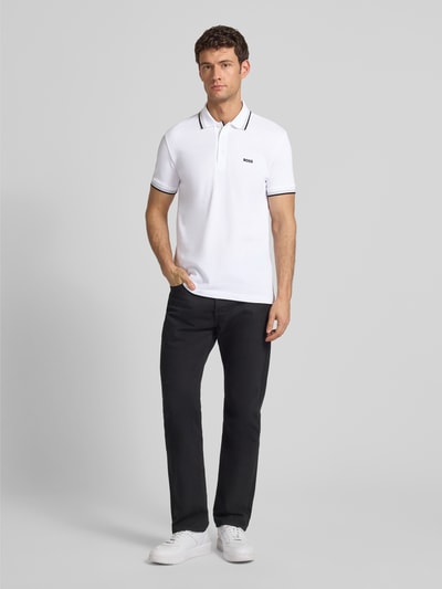 Männermodel trägt Regular Fit Poloshirt mit Label-Stitching Modell 'Paddy' von BOSS in Weiß, Baumwolle, Polokragen, Ganzkörperansicht von vorne.