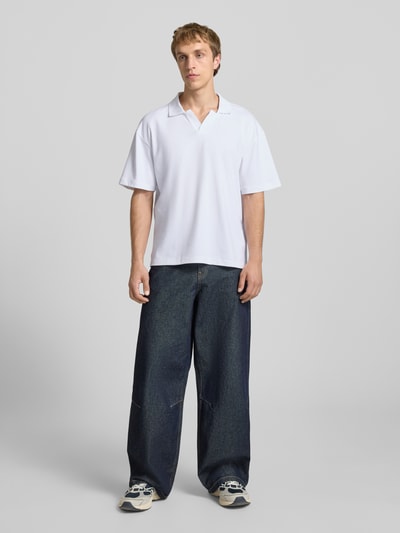 Männermodel trägt Boxy Fit Poloshirt aus Baumwoll-Mix Modell 'CASPIAN AIRLEX' von Only & Sons, weiß, kurzarm, unifarben, Polokragen, Label Patch, Jersey-Material, Ganzkörperansicht von vorne.