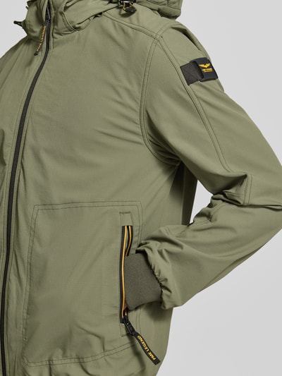 Männermodel trägt Jacke mit Kapuze und Reißverschlusstaschen von PME Legend in Olivgrün mit schwarzen Details, Material-Mix, Nahaufnahme Oberkörper.