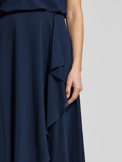 Frauenmodel trägt Knielanges Cocktailkleid mit Wasserfall-Ausschnitt von Christian Berg Cocktail aus dunkelblauem Chiffon, Wickeloptik, Detailaufnahme. Kontext: Taillierter Schnitt, Knielänge, breite Träger, Haken- und Reißverschluss, Rückenlänge bei Größe 36: 120 cm, Brustweite bei Größe 36: 45 cm.