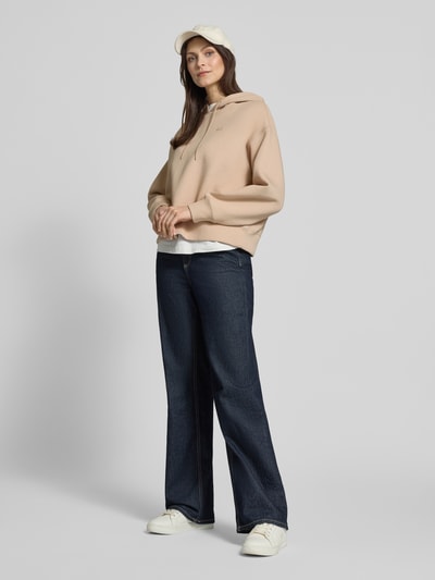 Frauenmodel trägt Oversized Hoodie aus Baumwoll-Mix von Lacoste Sport in Beige, unifarben, Logo-Detail, Ganzkörperansicht von vorne.