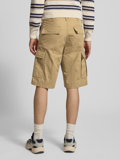 Mężczyzna nosi Shorts mit Cargotaschen od Carhartt Work In Progress, kolor beżowy, krój regular fit, tylne i boczne kieszenie, szerokość w rozmiarze 32: 43 cm, długość nogawki od wewnątrz 29 cm, widok całej sylwetki od tyłu.