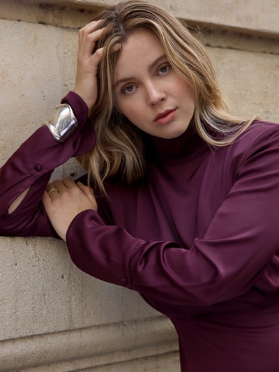 Vrouwenmodel draagt Fließendes Kleid in Maxilänge - curated by Isabelle Hartmann van Style Icon Collection, satijn, bordeauxrood, getailleerde pasvorm, lange mouwen, opstaande kraag, nahaufnahme bovenlichaam.