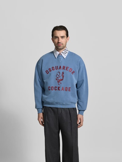 Männermodel trägt Regular Fit Sweatshirt mit Logo-Detail von Dsquared2, reine Baumwolle, Rundhalsausschnitt, elastische Abschlüsse, Ganzkörperansicht von vorne.