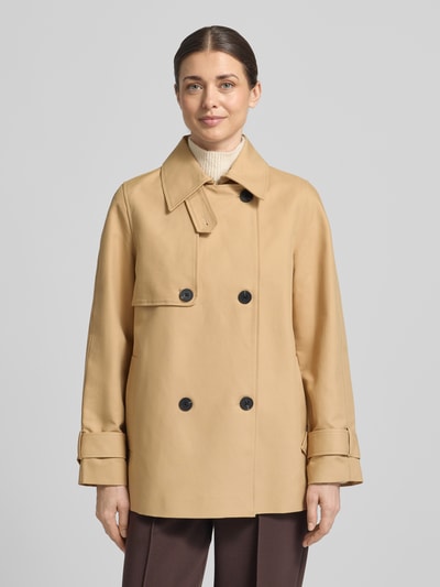 Frauenmodel trägt Trenchcoat mit Ärmelriegeln von Stefanel in Beige mit schwarzen Knöpfen, Umlegekragen, Zweireiher, Eingrifftaschen, Reine Baumwolle, Regular Fit, Ganzkörperansicht von vorne.